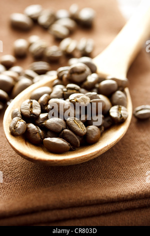 Kaffeebohnen in Holzlöffel auf braunem Tuch Stockfoto
