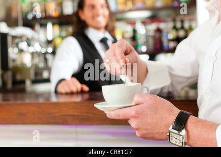 Coffeeshop - Barista Café mit einem Client, er trinkt Kaffee Stockfoto