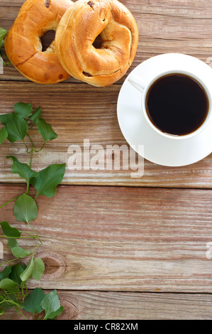 Tasse heißen Kaffee mit Bagels auf rustikalem Holz schlägt mit Exemplar Stockfoto