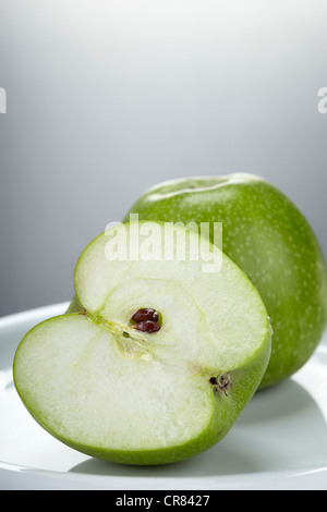 Zwei grüne Granny Smith Äpfel, einen ganzen Apfel und einen Apfel in zwei Hälften geschnitten Stockfoto