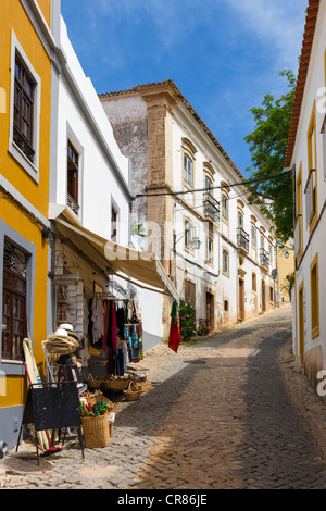 Dorfladen auf einen schmalen gepflasterten Straße führt bis zum Schloss in der Altstadt, Silves, Algarve, Portugal Stockfoto