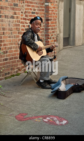 African American Street-Artist führt seine Gitarre spielen und singen auf einer amerikanischen Straße. Vertikale gegen eine Mauer Stockfoto