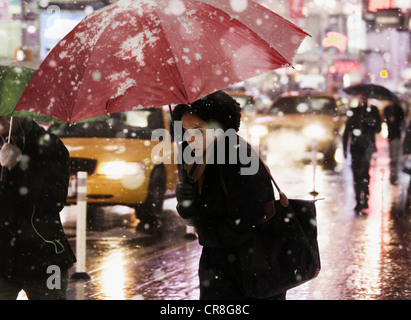 Frau zu Fuß durch Stadtstraße in Schneedusche Stockfoto