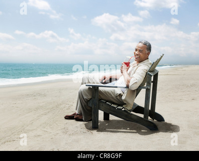 Reifer Mann in Stuhl am Strand entspannen Stockfoto