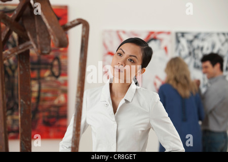 Junge Frau Blick auf Skulptur in Kunstgalerie Stockfoto