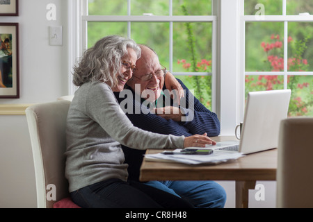 Älteres Paar mit Laptop zu Hause, lachen Stockfoto