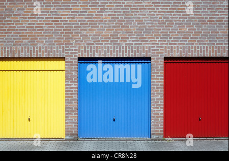 Drei Garagentore auf einer Wohnanlage in gelb, blau und rot lackiert Stockfoto
