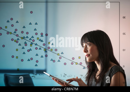 Reife Frau mit digital-Tablette mit Diagramm von Shapes-Fenster Stockfoto