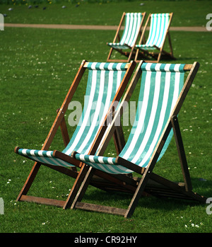 Vier Liegestühle auf dem Rasen mit Gänseblümchen in St. James Park, London Stockfoto