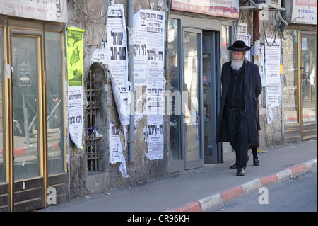 Straßenszene mit ein orthodoxer Jude und typische Wandzeitungen im Distrikt von Me'a She'arim oder Mea Shearim, Jerusalem, Israel Stockfoto