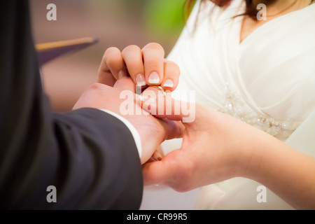 Bräutigam steckt Ring am Finger der Braut in der Kirche Stockfoto