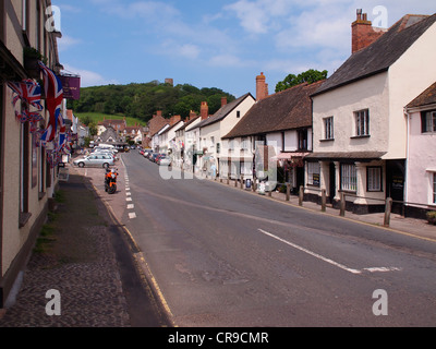 Dunster High Street mit Union Jack-Flaggen und strahlend blauem Himmel als ein Hintergrund Stockfoto