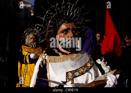 Eine maskierte Männer gekleidet als Matthaeus ein Relikt während einer Prozession der Karwoche in Puente Genil, Spanien hält Stockfoto