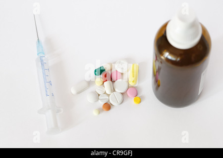 Spritze, Tabletten und Lösung in kleinen braunen Fläschchen auf weißem Hintergrund Stockfoto