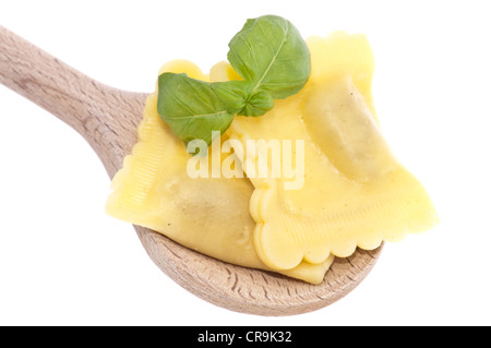 Ravioli auf einem Löffel aus Holz, verziert mit Basilikum Stockfoto