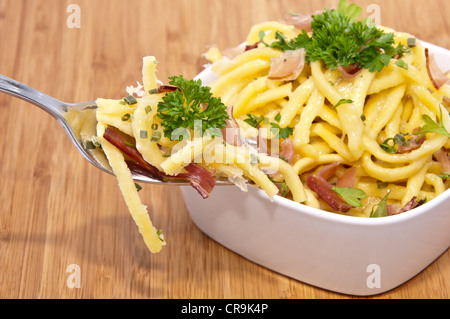 Käse-Spätzle mit Anteil an Gabel auf hölzernen Hintergrund Stockfoto