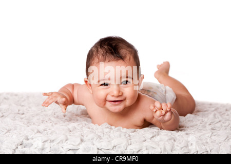 Niedliche glücklich lächelnden Baby Bauch auf weichen Untergrund tragen Windel, Handauflegen Blick in die Kamera, isoliert. Stockfoto