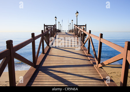 Holzmole in gutem Zustand mit Barrieren und Laternen auf einem ruhigen Mittelmeer in Marbella, Costa Del Sol, Spanien. Stockfoto