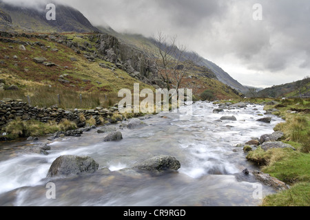 Das Wasser des Afon Nant Peris fließt durch den Pass von Llanberis in Richtung der Stadt Llanberis. Stockfoto