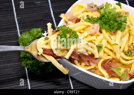 Portion Käse Spätzle in einer Schüssel mit Anteil an Gabel (auf schwarze Tischdecke) Stockfoto