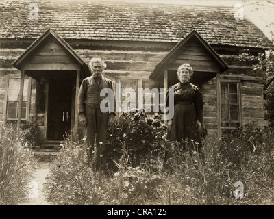 Älteres Ehepaar vor ungewöhnlichen Log Cabin Stockfoto