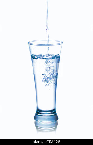 Foto von strömendem Wasser in Glas, isoliert auf weiß Stockfoto