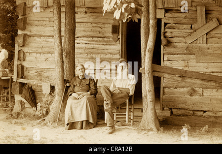 Älteres Ehepaar vor baufälligen Log Cabin Stockfoto