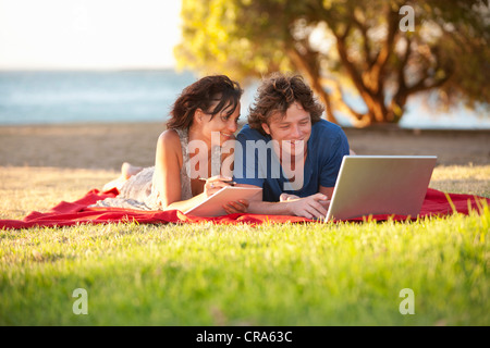 Paar mit Laptop auf der Picknickdecke Stockfoto