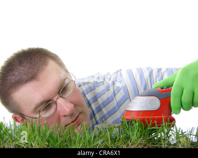 Junger Mann trimmen frische Gräser mit trimmer Stockfoto