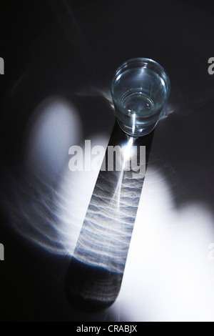 Glas Wasser in einem Strahl von Licht Stockfoto