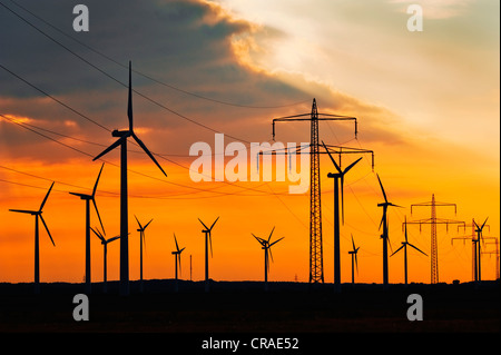 Windenergieanlagen und Strommasten gegen einen roten Abendhimmel, Cuxhaven, Niedersachsen, Deutschland, Europa, publicground Stockfoto