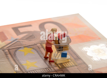 Miniatur Frau Figur schieben einen überquellenden Einkaufswagen auf einen 50 Euro beachten Sie, dass symbolisches Bild für shopping mania Stockfoto