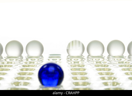 Ein blauer Ball vor einer Reihe von weißen Kugeln, symbolisches Bild für das Anderssein Stockfoto