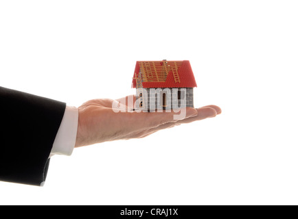 Des Mannes Hand, die ein Modell für ein Haus, symbolisches Bild für Hypotheken Stockfoto