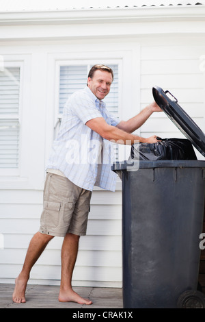 Lächelnder Mann Müll herausnehmen Stockfoto