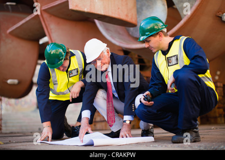 Arbeitnehmer, die Baupläne auf Trockendock zu lesen Stockfoto