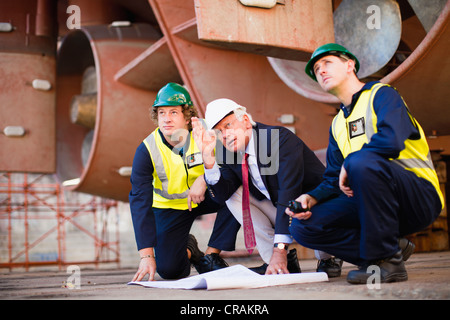 Arbeitnehmer, die Baupläne auf Trockendock zu lesen Stockfoto