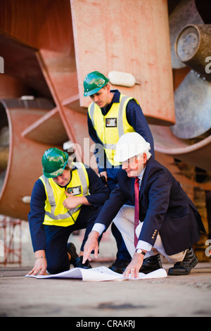 Arbeitnehmer, die Baupläne auf Trockendock zu lesen Stockfoto