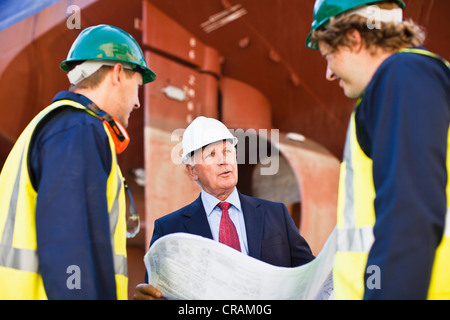 Arbeitnehmer, die Baupläne auf Trockendock zu lesen Stockfoto