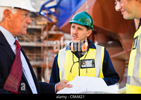 Arbeitnehmer, die Baupläne auf Trockendock zu lesen Stockfoto