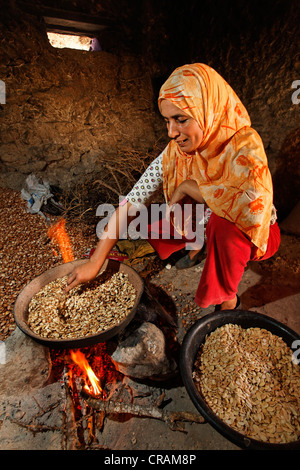 Frau Arganöl (Argania Spinosa) Mandeln rösten, über ein Feuer in ihrer Hütte für die traditionelle Herstellung von Argan-Öl Stockfoto