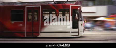 Verschwommene Straßenbahn, die durch den Bahnhofsplatz, Amsterdam, fährt. Stockfoto