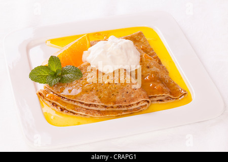 Klassisches französisches Dessert, Crepe Suzette, serviert mit Orange, Minze und einem Klecks Schlagsahne. Stockfoto