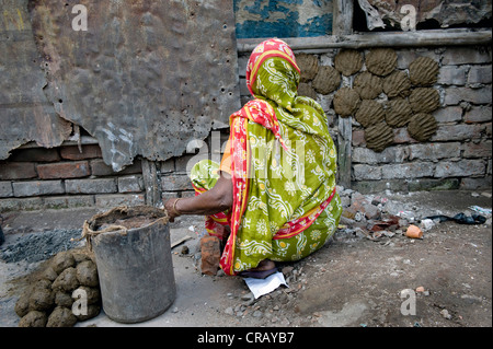 Frau drücken Kuhdung zum Trocknen an der Wand eines Hauses Shibpur Bezirk, Howrah, Kalkutta, Westbengalen, Indien, Asien Stockfoto