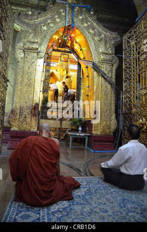 Burmesische Mönch und ein frommer älterer Mann sitzt im Gebet vor der heiligen Buddha-Statue des Landes, die goldene Stockfoto