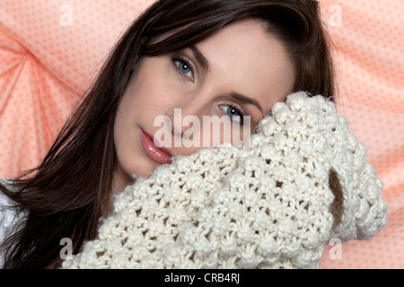 Junge Frau hält einen Schal um ihr Gesicht, Porträt Stockfoto