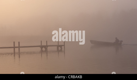 Dock und Boot im Nebel am See Staffelsee mit der Insel Woerth in der Nähe von Seehausen, Murnau, Bayern, Oberbayern Stockfoto