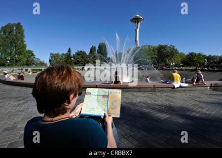 Frau hält einen Reiseführer von Seattle, International Brunnen vor der Space Needle, Seattle Center, Seattle Stockfoto