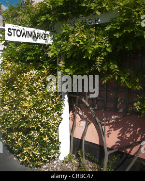 Dorf Richtung Straßenschild überwuchert an Hauswand Mendlesham, Suffolk, England Stockfoto