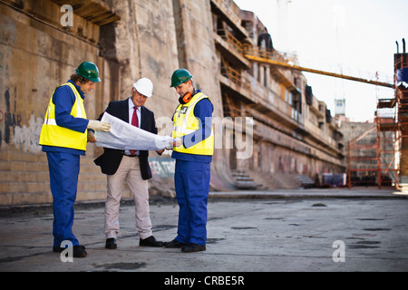 Arbeitnehmer, die Baupläne auf Trockendock zu lesen Stockfoto